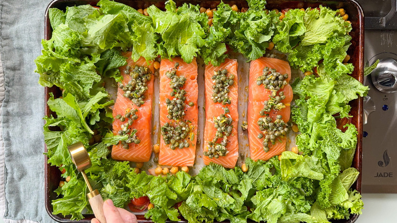 Raw salmon filets with caper topping and mustard greens drizzled with olive oil