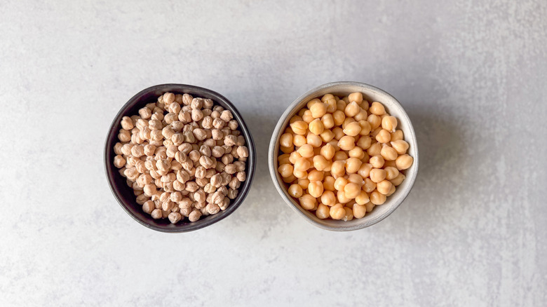 Dried and canned chickpeas in bowls on countertop