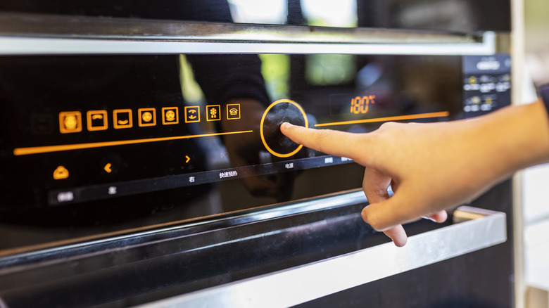 Finger pressing a button on an electric oven