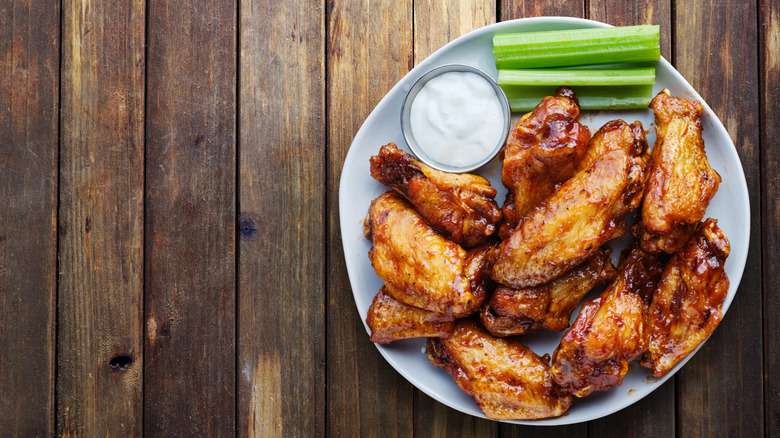 Barbecue chicken wings on a plate with ranch and celery
