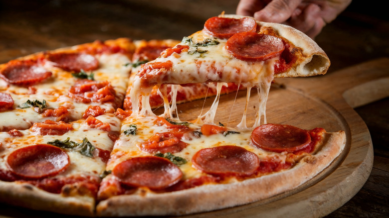 Person lifting a piece of pepperoni pizza