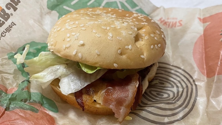 A burger is shown with bacon on it.