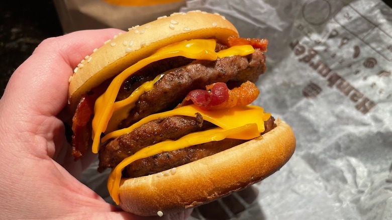 A bacon cheeseburger is shown with four patties.