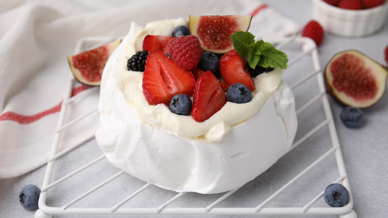 A mini pavlova garnished with whipped cream and fresh fruit