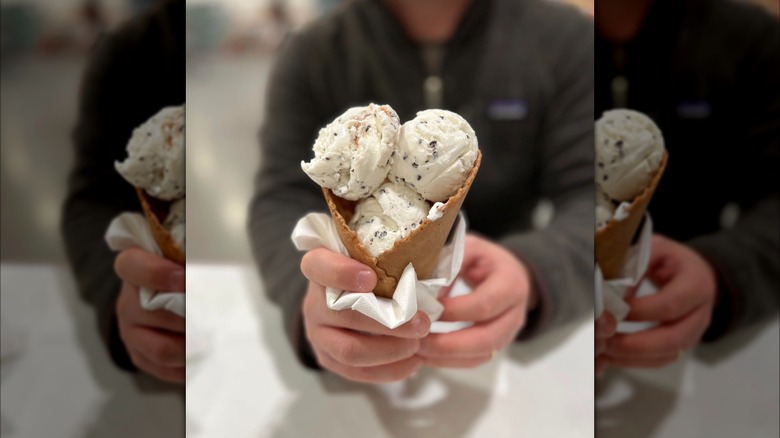 man holds waffle cone filled with scoops of gelato