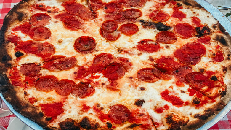 hand serving New York style pepperoni pizza