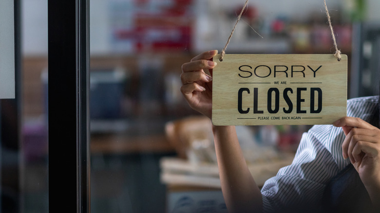 Two hands placing closed sign in window