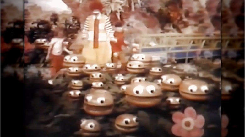 Image from old McDonald's McDonaldland commercial showing Ronald McDonald, a little girl, and a field of small hamburgers with faces