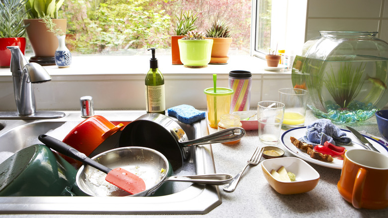 Cluttered dirty dishes filling sink and countertop