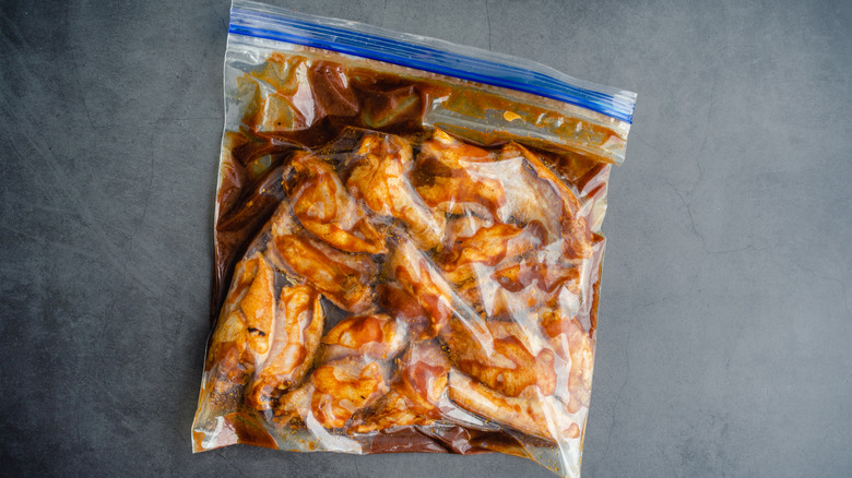 Raw chicken wings marinading in zip top bag on counter