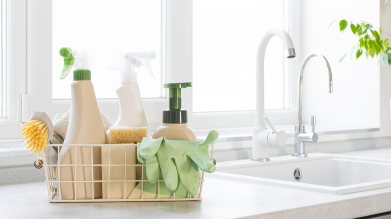 A variety of cleaning products in basket on countertop