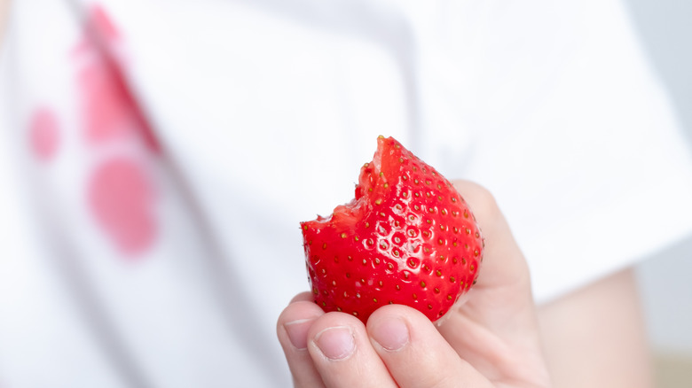 Holding strawberry with background stain