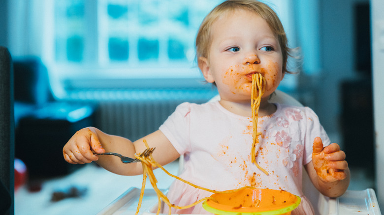 Child messily eating spaghetti