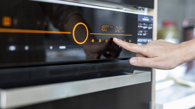 Woman setting temperature on oven