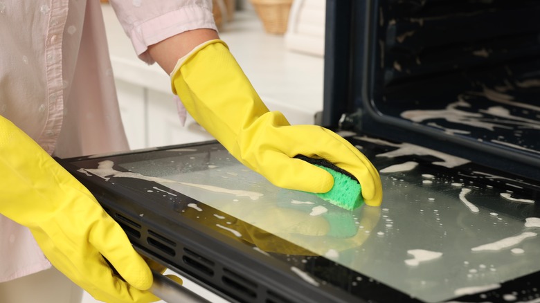 Woman with gloves cleaning oven