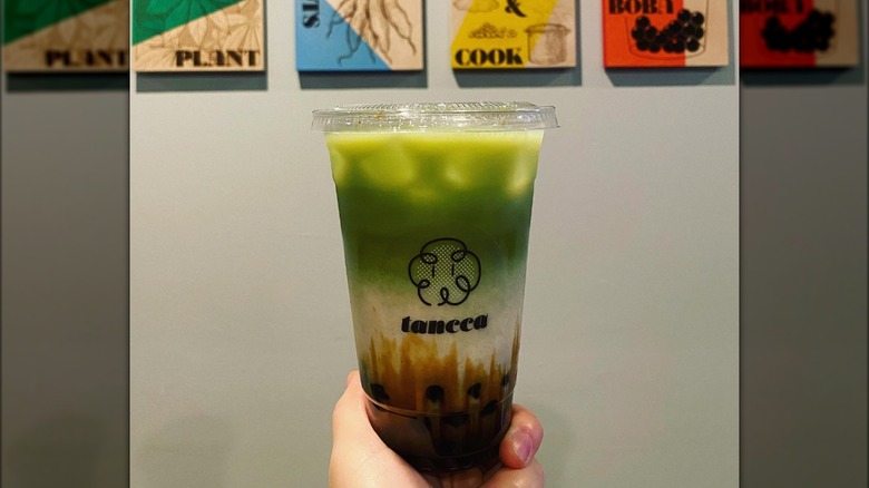 Hand holding a matcha bubble tea drink from Tancca, in San Francisco