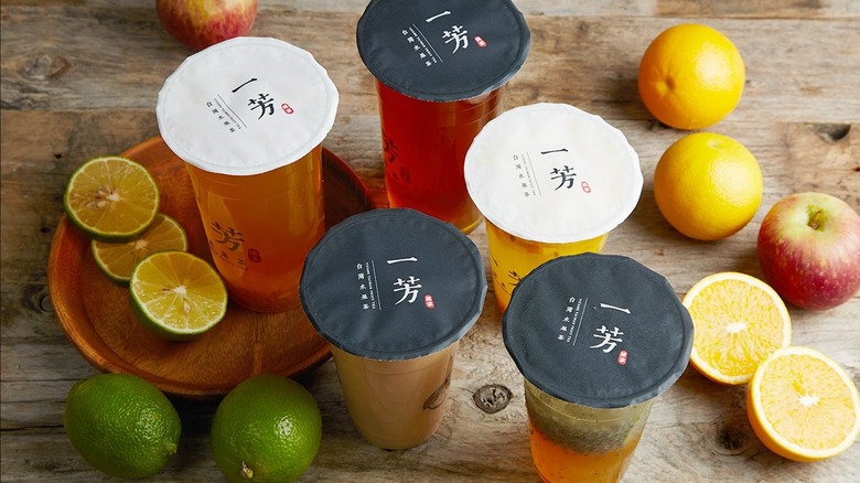 Five bubble teas from Yifang surrounded by lemons, limes, and apples