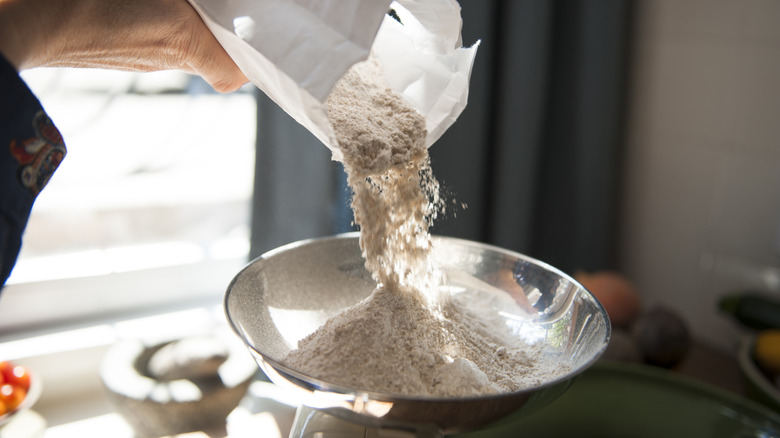 woman pouring bag of flour