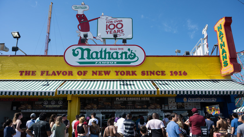 A crowd waits outside the Nathan's Famous hot dog spot