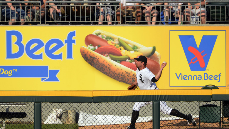 A baseball player runs in front of a Vienna Beef advertisement at a ball park