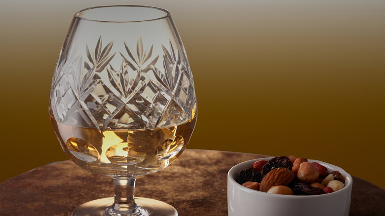 Crystal snifter of brandy and cup of nuts