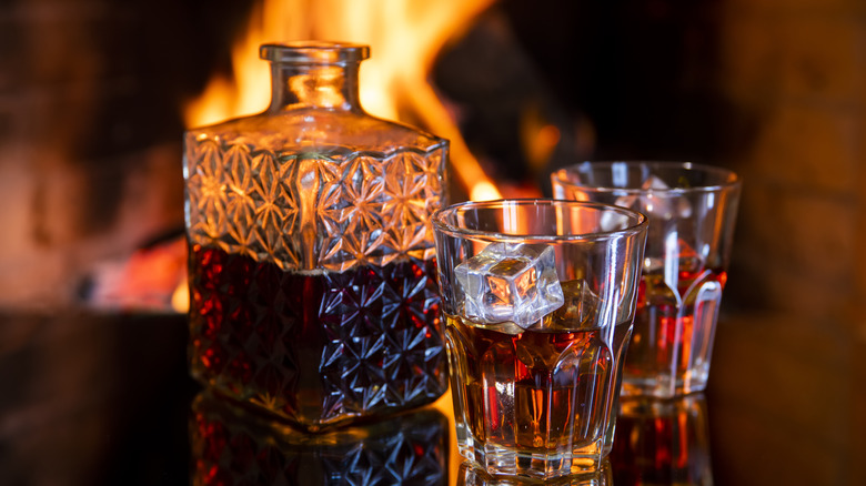 Two glasses of brandy with decanter in front of fireplace