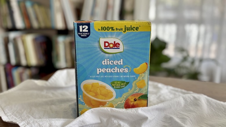 Dole Diced Peaches on table in front of shelf