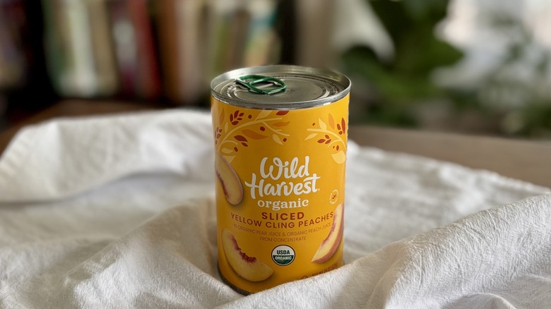 Wild Harvest Organic Sliced Yellow Cling Peaches on table in front of shelf