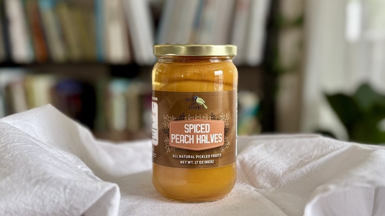 Green Jay Gourmet Spiced Peaches on table in front of shelf