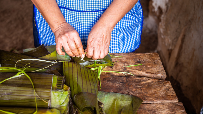 Woman folding tamales in banana leaves