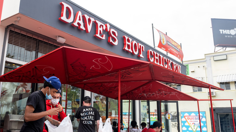 People congregating outside of a Dave's Hot Chicken counter