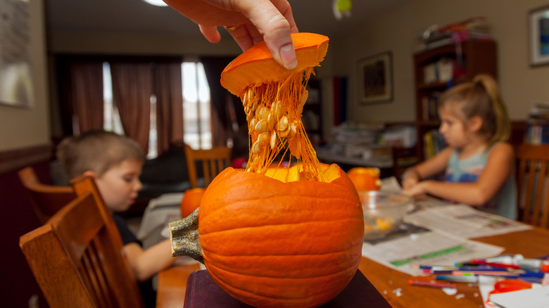 Person pulling out pumpkin flesh