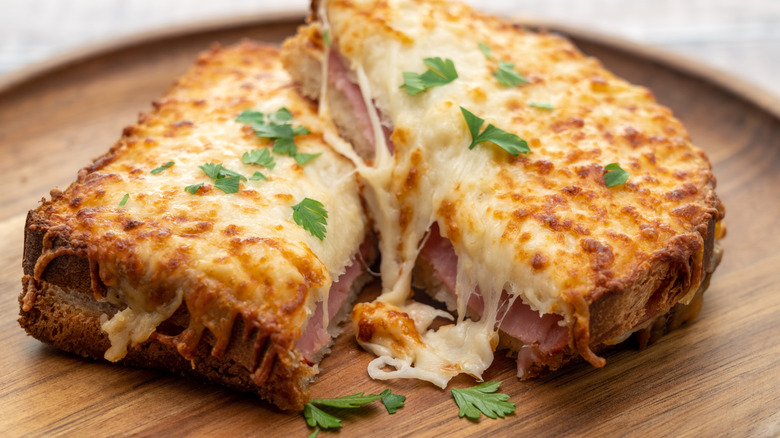 Halved croque monsieur on wooden plate