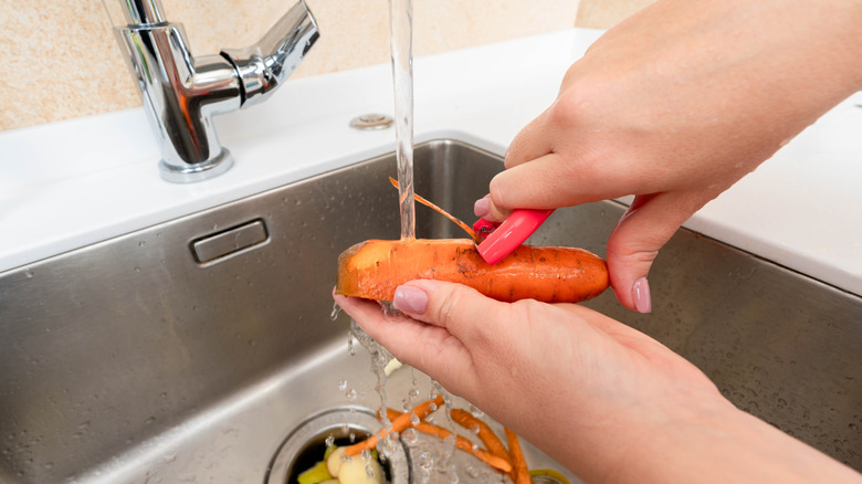 Person peeling carrot into sink