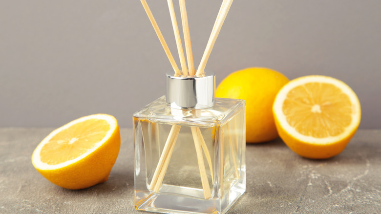 Halved lemons next to glass reed diffuser