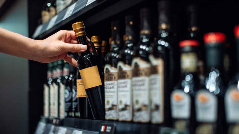 woman picking up vinegar off shelf