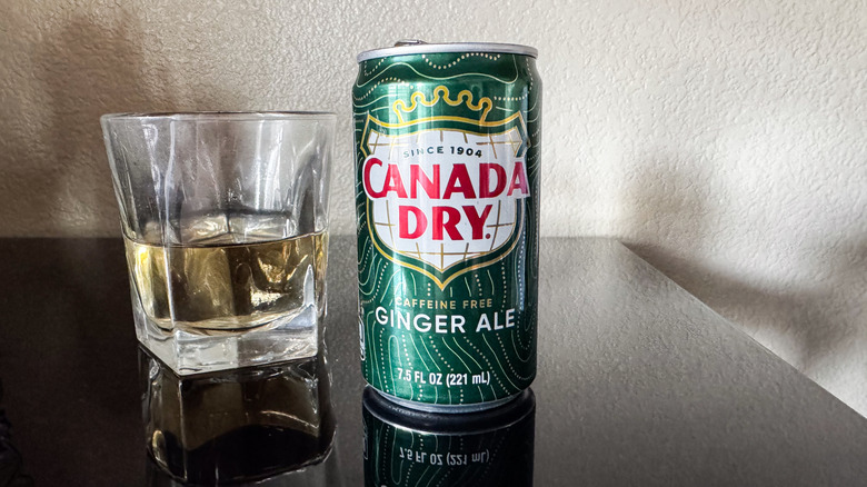 can of Canada Dry Ginger Ale with a glass half full of ginger ale next to it