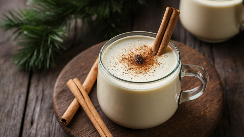 Glass mug of eggnog with cinnamon stick stirrer