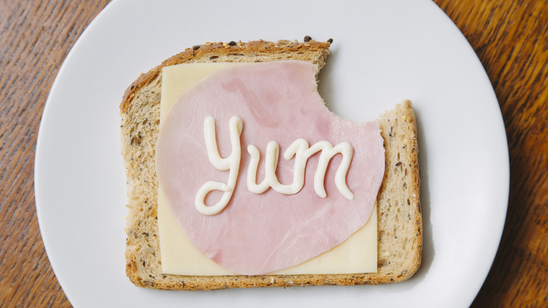 Open-faced sandwich topped with mayonnaise that spells "yum"