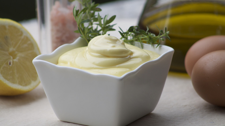 Square ramekin filled with mayonnaise surrounded by mayo ingredients