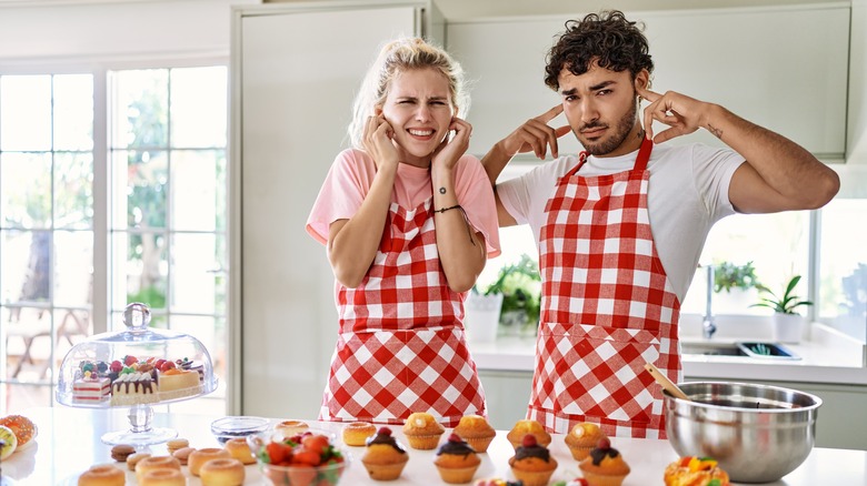 People covering their ears in a kitchen