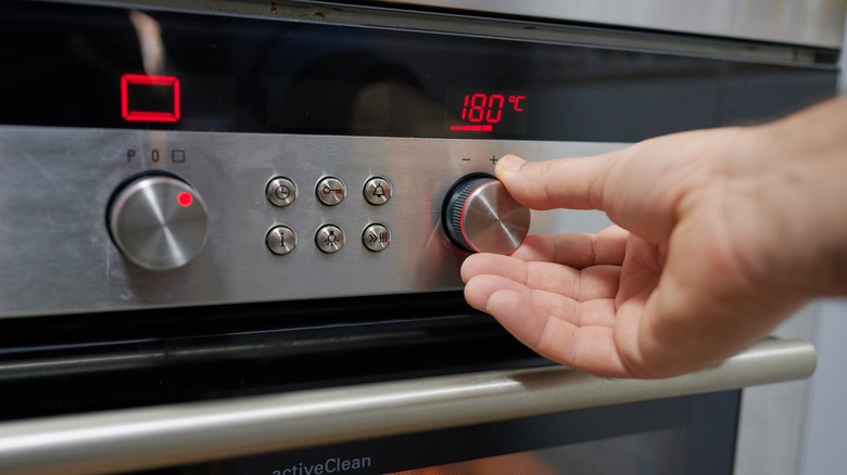 A person adjusting the oven temperature