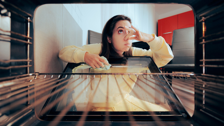 Woman cleaning a smelly oven