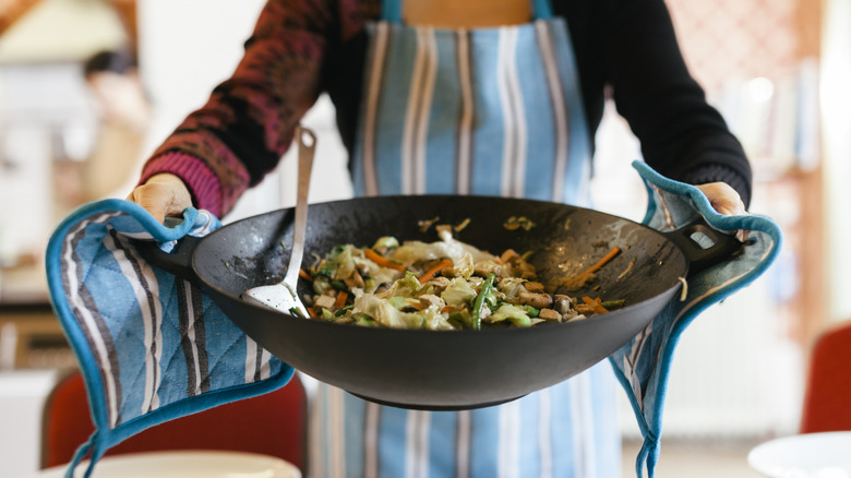 chef holding wok with vegetables