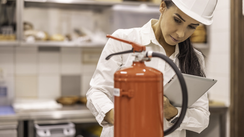 woman inspecting kitchen fire extinguisher