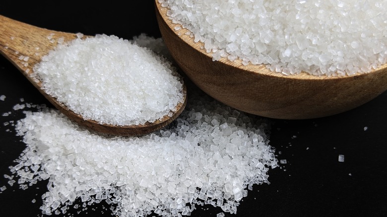 Wooden bowl and spoon of granulated white sugar