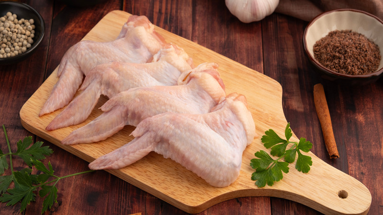 raw whole chicken wings on wooden tray