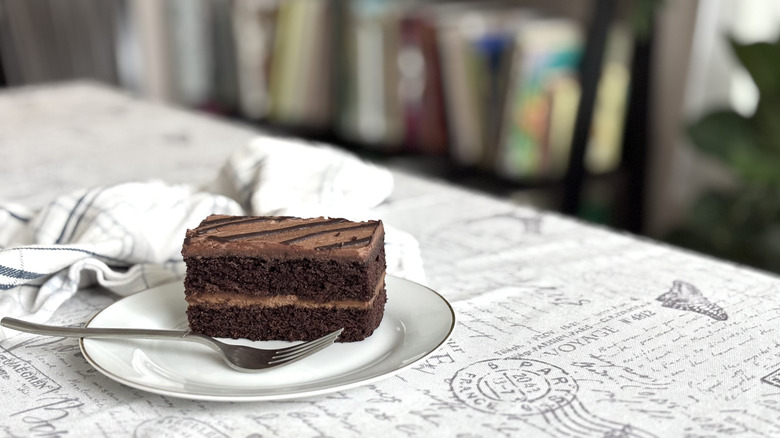 A slice of Whole Foods Chocolate Eruption Cake on a white ceramic plate with a fork