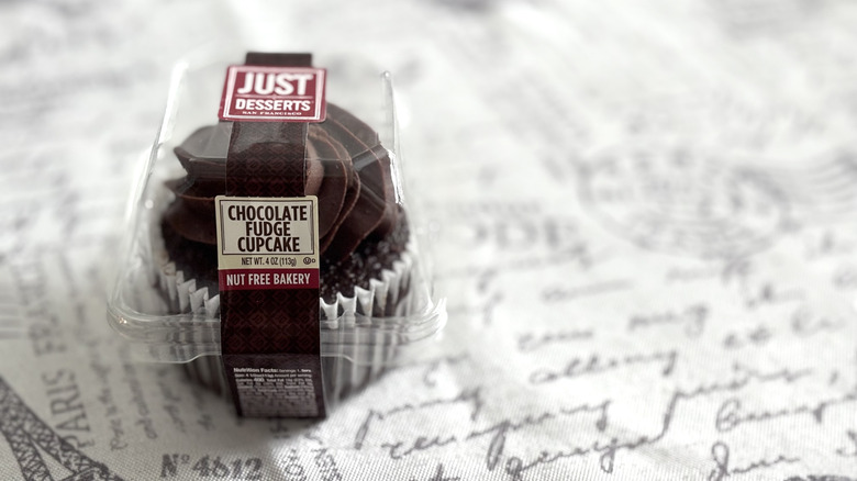 A packaged Just Desserts Chocolate Fudge Cupcake on Paris-themed tablecloth