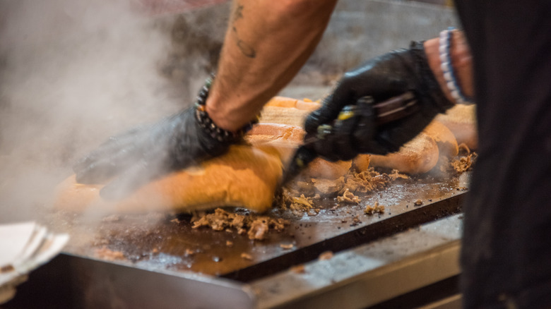 Cheesesteaks cooking on flattop griddle